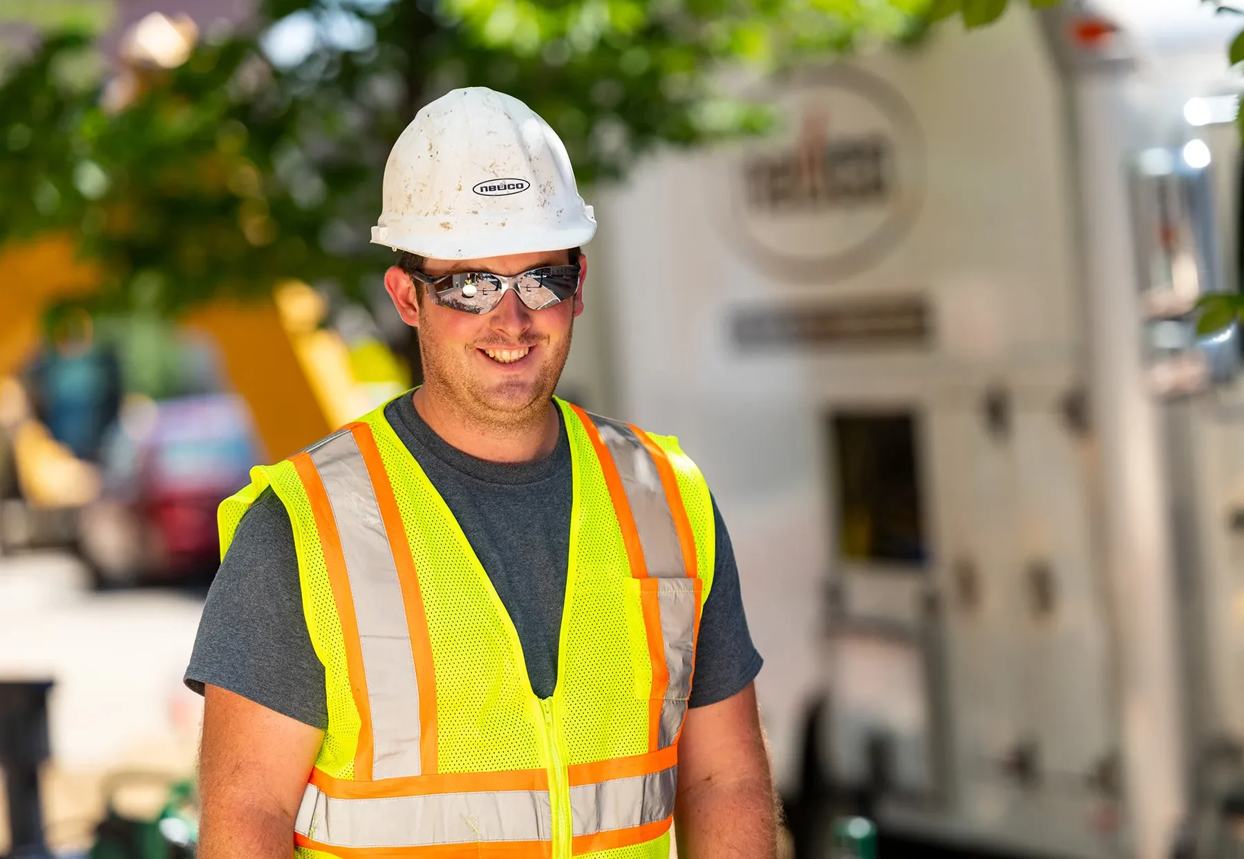 Worker in safety equipment and sunglasses smiling