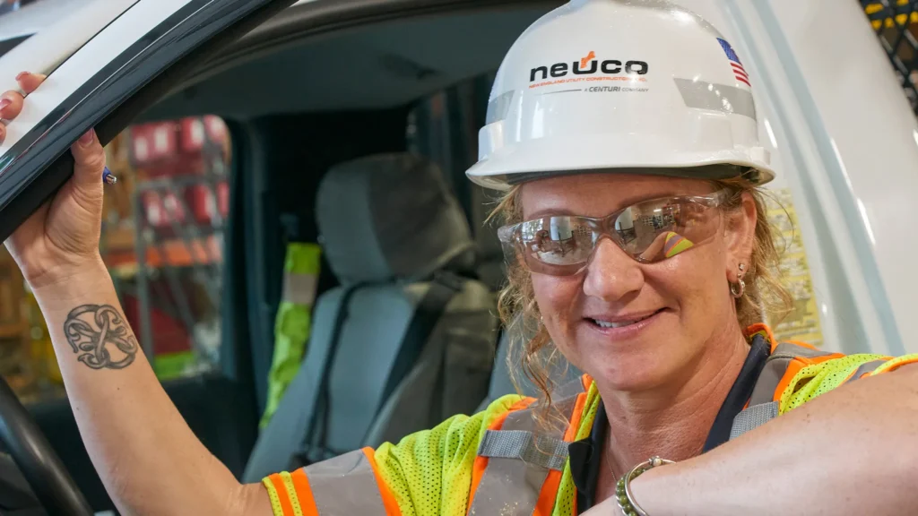 Neuco employee smiling in safety glasses and hard hat